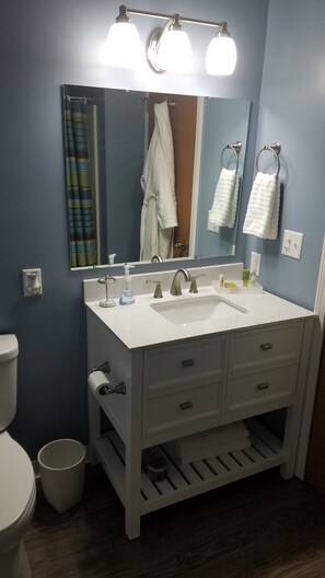 Un baño con tocador blanco, un espejo grande, un perchero y un inodoro.
