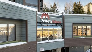 Um edifício com uma placa 'Snowblaze', um aviso de queda de gelo e vista de uma paisagem nevada através de grandes janelas.