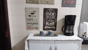 Eine Küchenzeile mit Kaffeemaschine, zwei Tassen und einem Schild mit der Aufschrift: 'Vergiss nie, morgens besseren Kaffee zu trinken, denn er ist gut.'