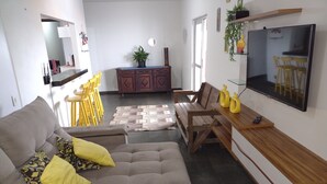 Ein Wohnzimmer mit einer Couch, einem Holztisch und einem an der Wand befestigten Fernseher.