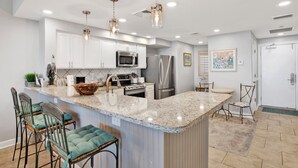 Una cocina moderna con armarios blancos, electrodomésticos de acero inoxidable y una isla de granito.