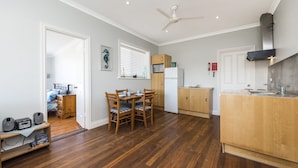 A compact kitchen with wooden cabinets, a white refrigerator, and a dining area with a table and chairs.