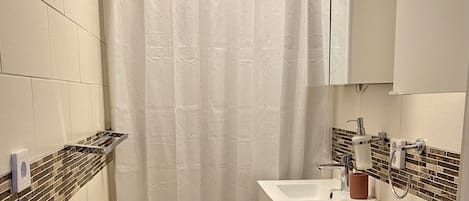 Un baño con cortina de ducha, inodoro, lavamanos y espejo.
