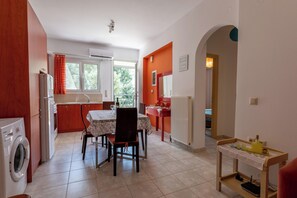 Une cuisine compacte comprenant une table à manger, des chaises, un lave-linge et une petite table sur laquelle sont posés divers objets.