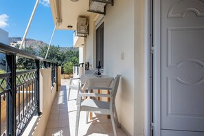 A balcony with a table and chairs, a white door, and a view of the surrounding area.
