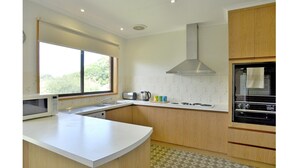 Eine moderne Küche mit einer zentralen Kochinsel, einem eingebauten Backofen und einem Fenster, das für natürliches Licht sorgt.