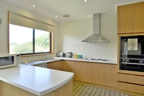 A modern kitchen with a central island, a built-in oven, and a window providing natural light.