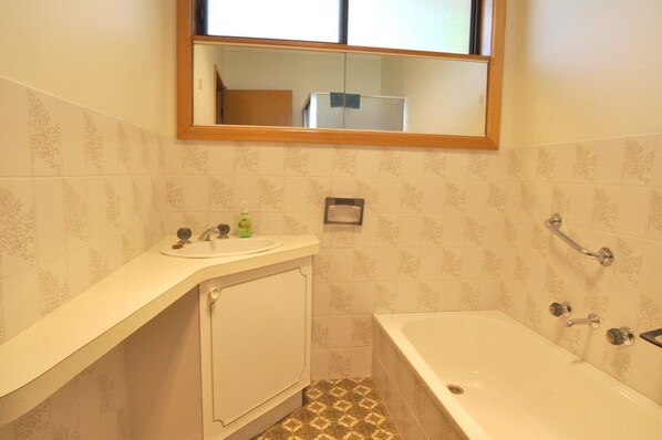 A bathroom with a bathtub, a sink with a mirror above it, and a toilet.