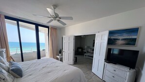 Una camera da letto con un letto, un ventilatore a soffitto, una TV e vista sull'oceano.