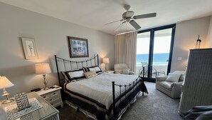 Ein Hotelzimmer mit einem großen Bett, einem Deckenventilator, Meerblick, einem Balkon und einer Sitzecke.