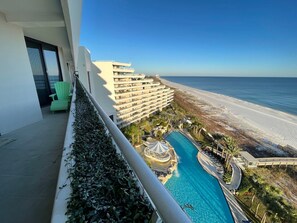 Ein Hotelbalkon mit Pool, Blick auf Strand und einem mehrstöckigen Gebäude.