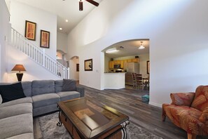Relax in this stylish living area with a sofa, coffee table, and armchair, leading up to an upper level and a modern kitchen.