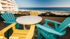 Une table ronde entourée de chaises, une vue sur l’océan et un bâtiment en arrière-plan.