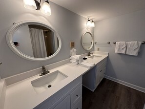 A modern bathroom with two sinks, a large mirror, and a towel rack. - Gulf Front Condo with Stunning Views! (Pensacola)