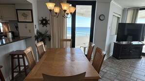 Ein Essbereich mit Holztisch und -stühlen, einer Kristallleuchter, einer Uhr und einem Fernseher auf einem Schrank.