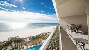Un balcon avec vue sur une plage et une piscine.