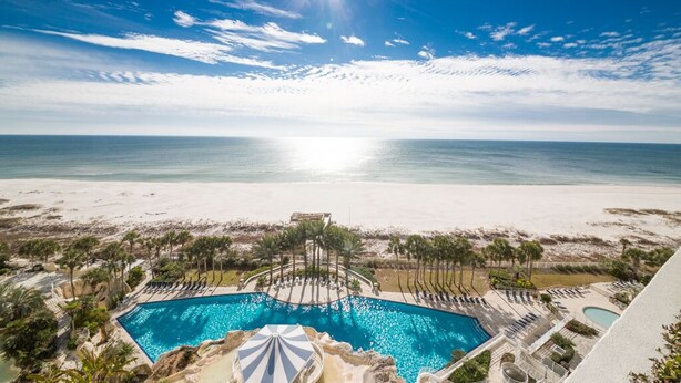 Un espace piscine offrant une vue sur la plage et l’océan.