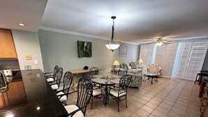 A spacious living area with a dining table, chairs, a sofa, and a ceiling fan. - Gulf Front Condo with Stunning Views! (Pensacola)