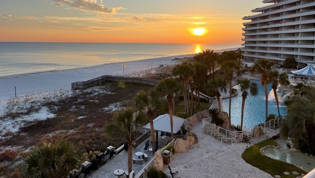 A resort with a view of the sunset over the ocean, a pool area, and a beach. - Gulf Front Condo with Stunning Views! (Pensacola)