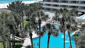 A resort with a central pool surrounded by palm trees, a beach, and a multi-story building with balconies. - Gulf Front Condo with Stunning Views! (Pensacola)