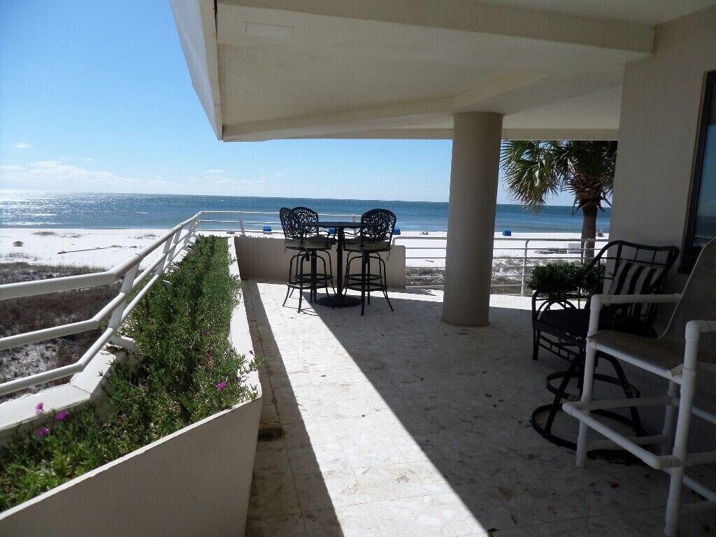 Un espacio de estar al aire libre cubierto con vista a la playa y al océano.