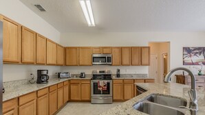 A kitchen with wooden cabinets, a stainless steel sink, granite countertops, a microwave, a coffee maker, and a stainless steel oven. - Renewed luxury property 20 min from Disney and major parks (Davenport)
