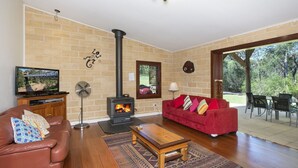 Una sala de estar con pared de ladrillo, chimenea, sofá rojo, mesa de centro de madera y televisor.