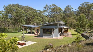 Una casa moderna de dos pisos con patio, mobiliario exterior y piscina.