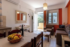 Een woonkamer met een eethoek, een bank, een televisie en een balkon met uitzicht.