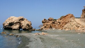 Ein felsiger Strand mit großen Felsen und blauem Himmel.
