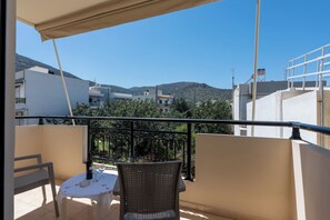 Un balcon avec une table, des chaises et une bouteille de vin.