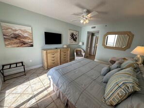Ein Schlafzimmer mit Bett, Fernseher, Deckenventilator und Bildern an den Wänden.