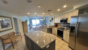 A modern kitchen with granite countertops, stainless steel appliances, and a large island. - Gulf Front Condo with Stunning Views! (Pensacola)
