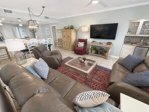 A modern living room with leather sofas, a coffee table, and a flat-screen TV.
