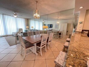 A spacious living area with a dining table, chairs, and a kitchen counter.