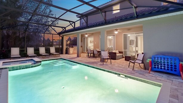 Un espace piscine avec des chaises longues, un coin repas et une terrasse couverte.