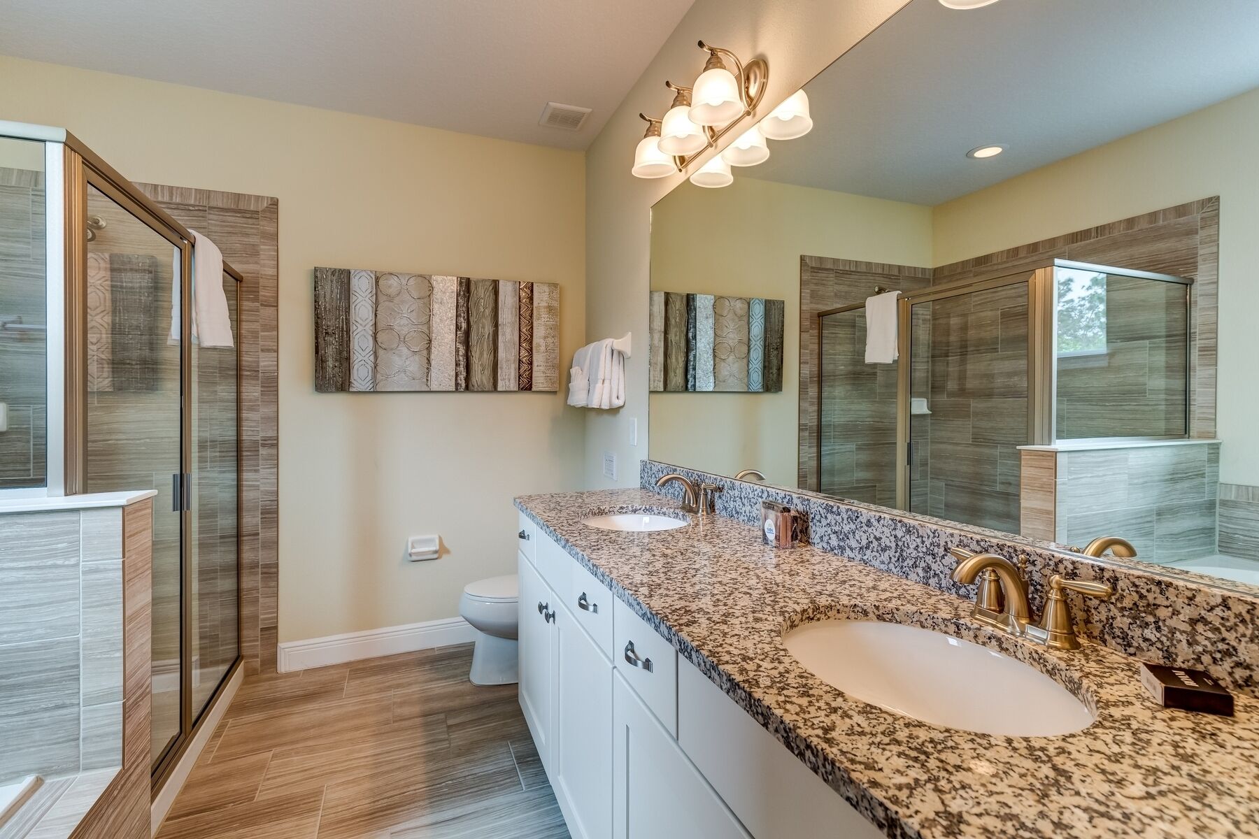 A modern bathroom with two sinks, a large mirror, and a shower enclosure.