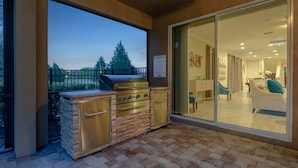 Une terrasse extérieure équipée d’un barbecue et d’une porte-fenêtre coulissante donnant sur un espace de vie intérieur.