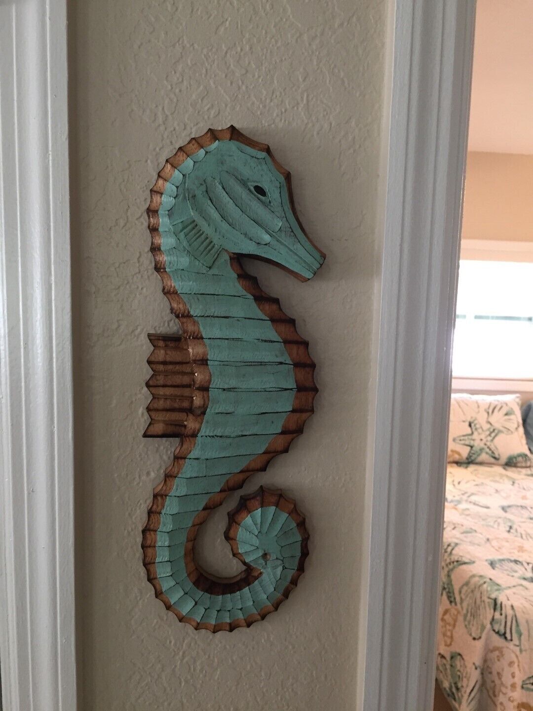 A teal seahorse wall decoration on a white door.