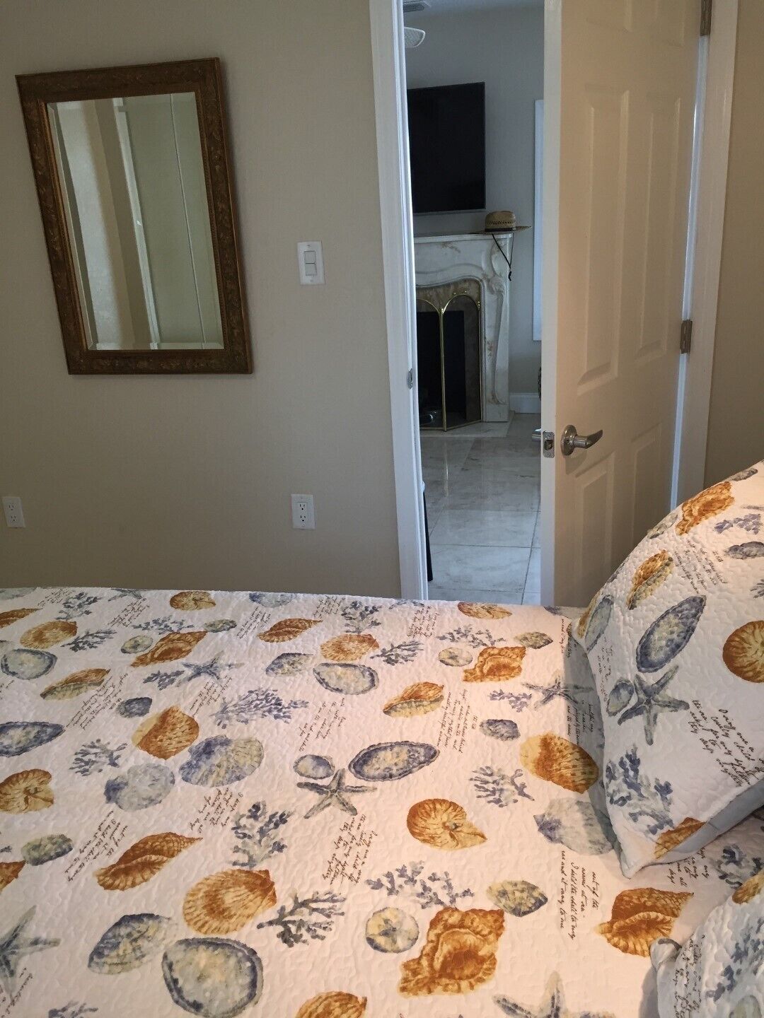 Un dormitorio con cama, espejo y puerta que da a un baño.