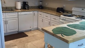 Una cocina con gabinetes blancos, encimera de granito, estufa y lavabo.