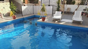 A swimming pool with two white lounge chairs and potted plants. - Nile Jewel Suites Luxor Egypt , Luxury fully Serviced Nile View Apartment  (Qurna)