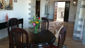 A dining area with a round table, four chairs, a vase with flowers, and a painting on the wall. - Nile Jewel Suites Luxor Egypt , Luxury fully Serviced Nile View Apartment  (Qurna)