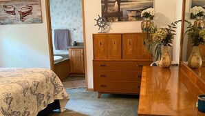 Quarto com cama, penteadeira e pintura de um casal.