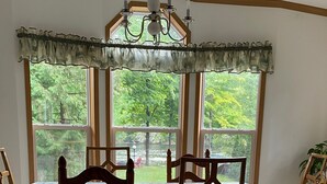 Uma área de refeições com uma mesa coberta por um tecido de mesa estampado com flores, cercada por cadeiras de madeira com encosto decorativo.