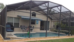 A screened-in pool area with a covered patio, chairs, and a small table. - SOUTHERN DUNES VILLA - GOLF! POOL! CLOSE TO DISNEY, LEGOLAND, UNIVERSAL! (Haines City)