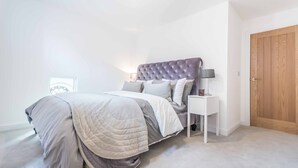 Ein Schlafzimmer mit Bett, Nachttischen, einer Lampe und einer Tür.