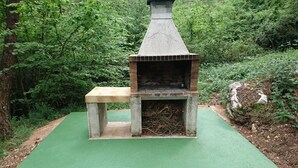 A brick-built outdoor oven with a bench in a forested area. - Charming house located in the Espinalbet area. (Castellar del Riu)