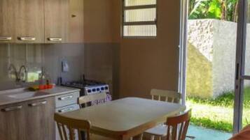 Una cocina compacta con muebles de madera, una estufa a gas y un comedor con dos sillas.
