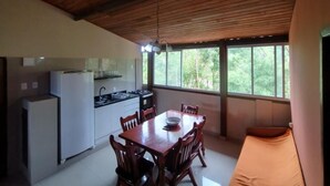 A compact kitchen with a dining area, wooden ceiling, and large windows. - Apart da Cachoeira (Florianópolis)